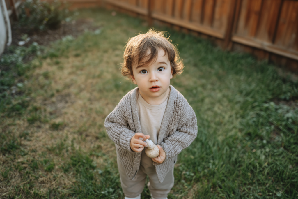 un ninio usando un sueter en un jardin