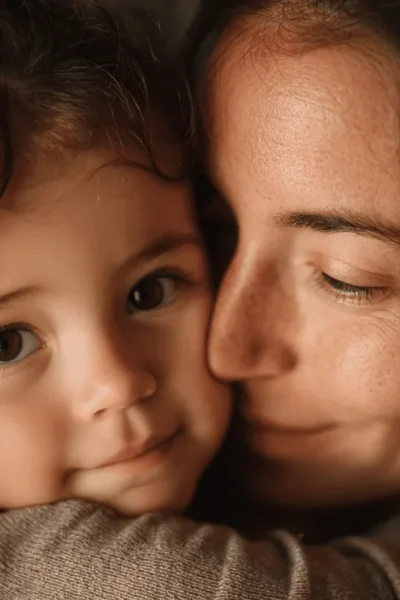 Madre abraza a su hija mientras ambas sonríen.